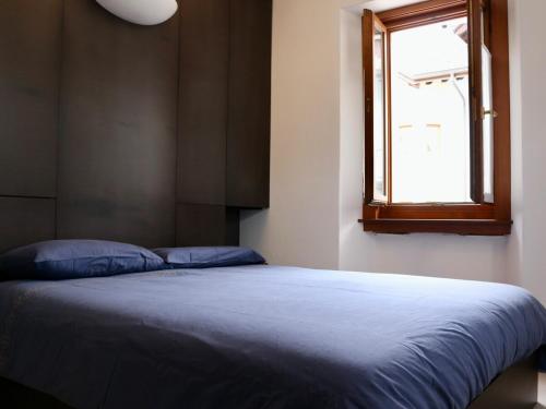 1 cama con manta azul y ventana en White Nest Apartment, en Ponte di Legno