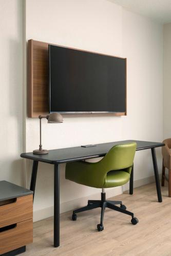 a desk with a green chair and a television on a wall at Fairfield Inn and Suites Jacksonville Beach in Jacksonville Beach