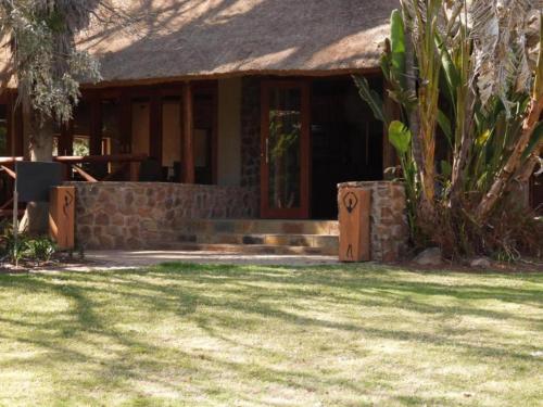 a house with a stone wall and a porch at The Lions Foundation Rescue & Conservation Centre at Schrikkloof in Warmbaths