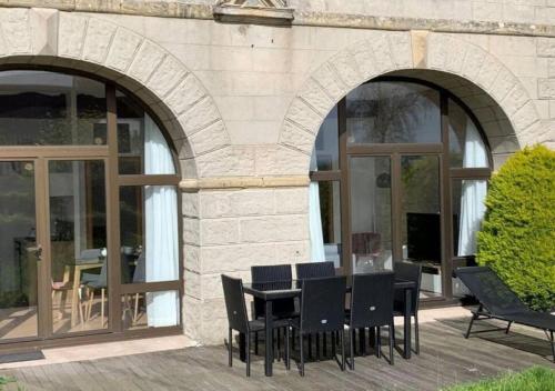 a patio with a table and chairs in front of a building at Appartement lumineux et cosy avec jardin vue sur chateau près Port en Bessin, Bayeux et Omaha Beach in Commes