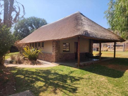 a house with a thatched roof in a yard at The Lions Foundation Rescue & Conservation Centre at Schrikkloof in Warmbaths