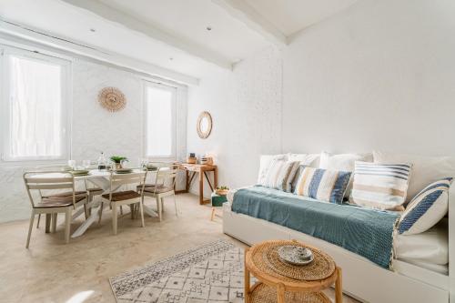 Cette chambre blanche comprend un lit et une table à manger. dans l'établissement Les Fincas du Port - Studios en ville avec vue, à La Ciotat