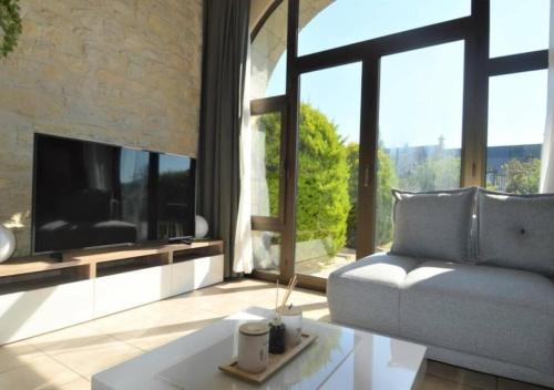 a living room with a couch and a tv at Appartement lumineux et cosy avec jardin vue sur chateau près Port en Bessin, Bayeux et Omaha Beach in Commes