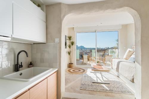 Il dispose d'une cuisine avec un évier et d'un salon avec un canapé. dans l'établissement Les Fincas du Port - Studios en ville avec vue, à La Ciotat