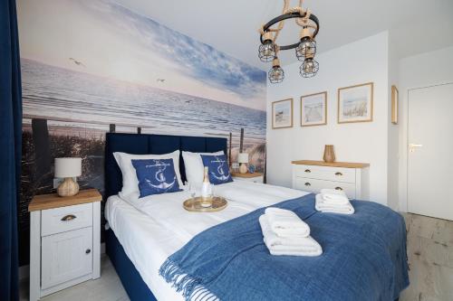 a bedroom with a blue and white bed with towels on it at Rezydencja Merwede Aparthotel - My Rest in Gdańsk