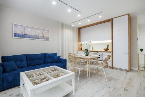 a living room with a blue couch and a table at Rezydencja Merwede Aparthotel - My Rest in Gdańsk