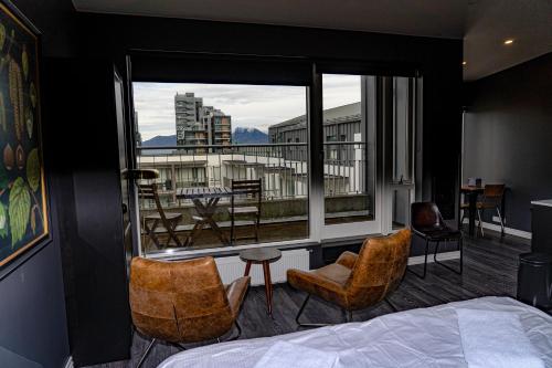a bedroom with a bed and chairs and a balcony at Vintage Apartment Hotel in Reykjavík