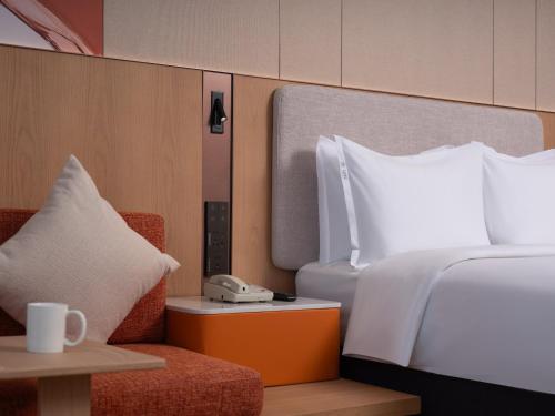 a bedroom with a bed and a telephone and a chair at Holiday Inn Express Shangdi Beijing by IHG l Next to The Old Summer Palace & Qinghe Railway Station & Subway l Taxi 15 Minutes to Summer Palace & Peking University & Tsinghua University l 20 Minutes to Badaling Great Wall by Railway in Beijing