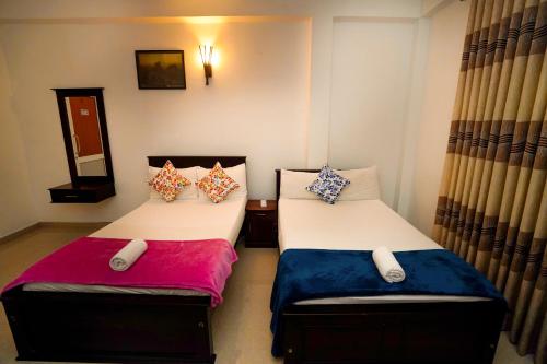 two twin beds in a room with curtains at Airport 4 Season Transit Hotel in Katunayake