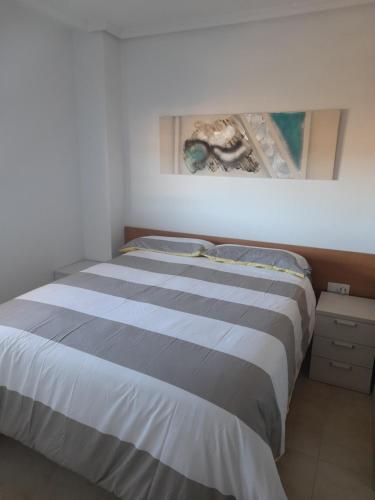 un letto in una camera da letto con un dipinto sul muro di Ático Primera línea de playa Playa Dorada a El Borseral