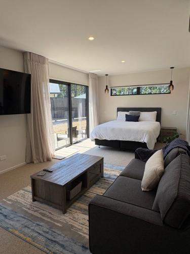 Un dormitorio con una cama, un sofá y un televisor. en Mountain Abode Studio, en Methven