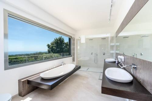 ein Badezimmer mit zwei Waschbecken und einem großen Fenster in der Unterkunft Villa Persea in Santa Venerina