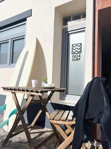 a wooden table and chair next to a building at GO4SURF beach Lofts in Peniche