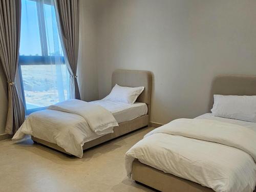 two beds in a room with a large window at شاليه دار هوم ببريده in Buraydah