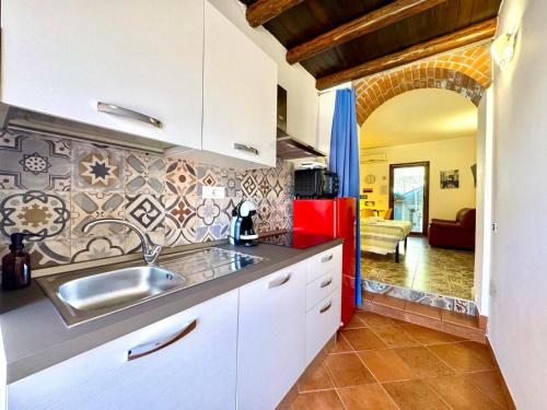 a kitchen with a sink and a red refrigerator at Le Corti Sarde Countryside in Bari Sardo