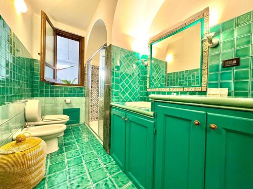 a green bathroom with two toilets and a sink at Le Corti Sarde Countryside in Bari Sardo