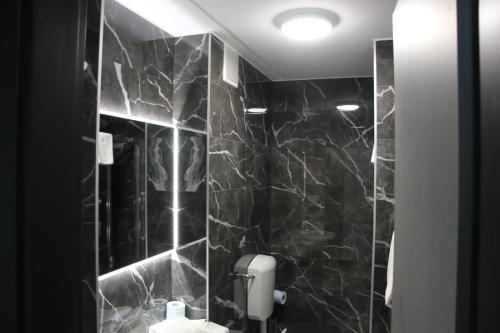 a bathroom with black marble walls and a toilet at Green Hotel in Vergiate