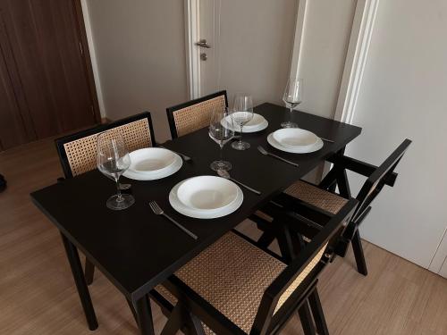 a black table with plates and wine glasses on it at Entire apartment near train station with pool & views in Ban Song Hong