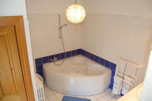 La salle de bains est pourvue d'une baignoire blanche et d'un mur carrelé bleu. dans l'établissement Château de Camboulan, à Ambeyrac