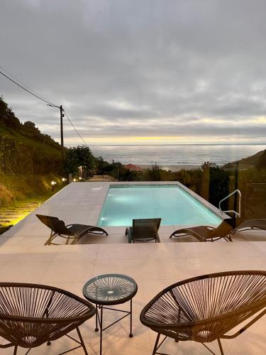 a swimming pool with two chairs and two tables and chairs at Balcobo Villas&Cabañas in A Coruña