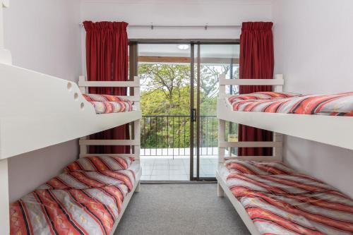 a room with three bunk beds and a balcony at Unit 4 Springvale in Zinkwazi Beach