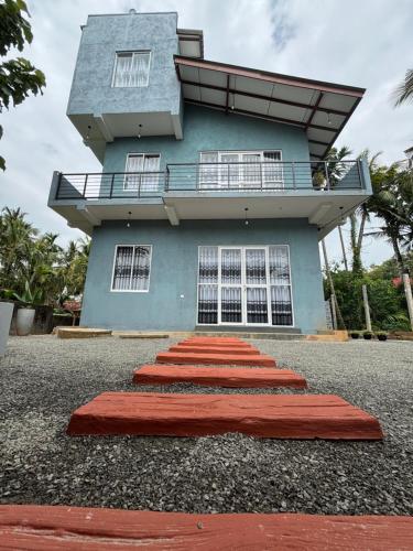 a blue building with red mats in front of it at Noble Nest Hirikatiya in Dickwella