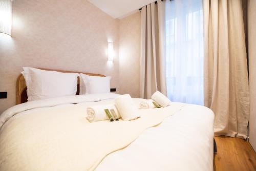 une chambre avec un lit avec des draps blancs et une fenêtre dans l'établissement CIA - Nation - Lovely Parisian Escape, à Paris