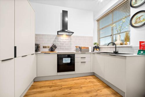 a kitchen with white cabinets and a sink and a window at Stylish Two-Bedroom Apartment with Balcony & Parking 9NC in Birmingham