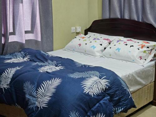 a bed with a blue and white blanket on it at RAX Apartment3 in Dodoma