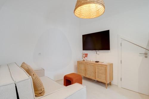 a living room with a white couch and a tv at Casa Do Beco in Moura