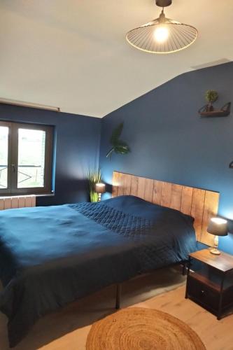 une chambre avec un grand lit avec un mur bleu dans l'établissement Gîte de Briante, à Saint-Lager