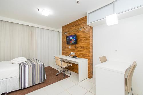 a bedroom with a bed and a desk and a tv at Vision Hotel em Brasília 59854 in Brasilia