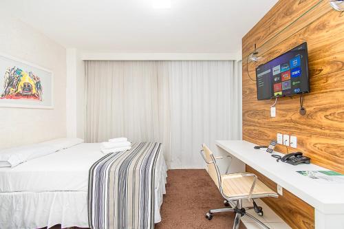 a hotel room with a bed and a desk and a tv at Vision Hotel em Brasília 59854 in Brasilia