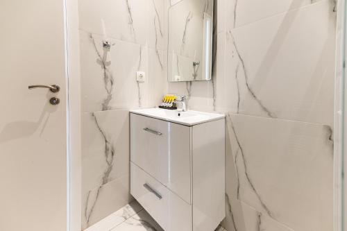 biała łazienka z umywalką i lustrem w obiekcie Stylish spacious apartment in Palaio Faliro (C1) w Atenach