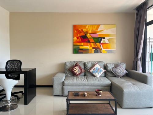 a living room with a couch and a painting at Stunning 60 sqm Studio at NaiHarn Beach Condo, Walk to Beach, Your Tropical Retreat! in Rawai Beach
