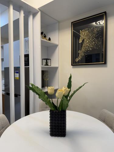 a white table with white roses in a black vase at Cayenne - Two Bedroom Condo Unit in Davao City