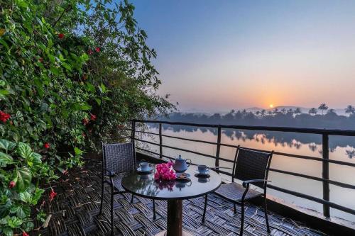 a table and chairs on a balcony with a view of the water at Banyan Tree Pool Villa at Surya River Thane in Pālghar