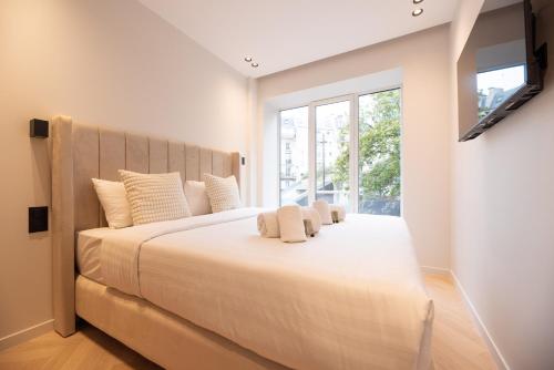un grand lit blanc dans une chambre avec une fenêtre dans l'établissement CIA - Châtelet-Marais Delight 4P, à Paris