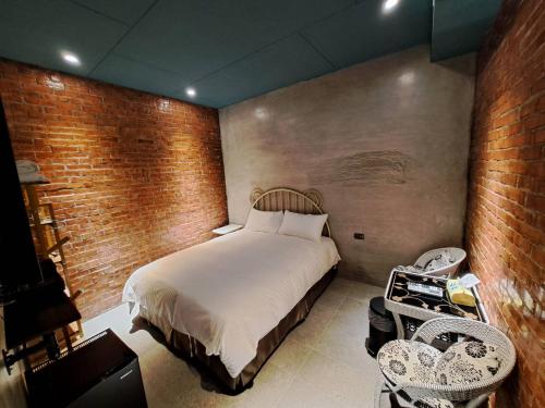 a bedroom with a bed and a brick wall at Chunfang Residence in Fangliao