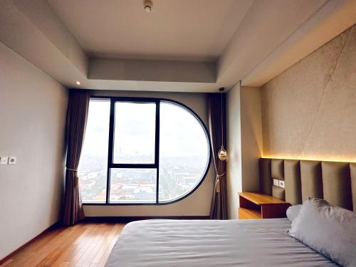 a bedroom with a large window and a bed at Stylish 2BR Apartment ARC100 Surabaya City Centre with Balcony by Le Ciel Hospitality in Surabaya