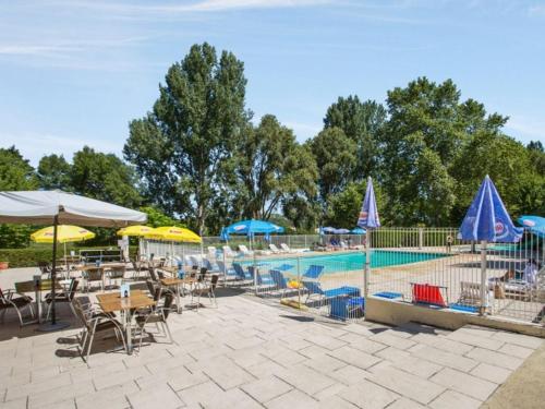 une piscine avec tables, chaises et parasols dans l'établissement Camping maeva Escapades Les Bö-Bains, à Badefols-sur-Dordogne