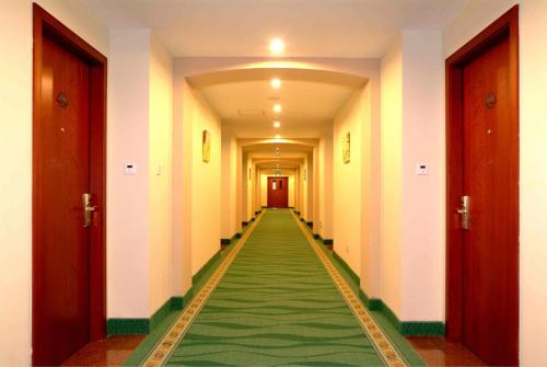 a long hallway with a green carpet in a building at GreenTree Inn Hebei Langfang Development Zone Convention and Exhibition Centre Business Hotel in Langfang