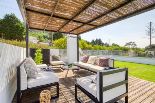 a patio with a wooden pergola and chairs and a table at Casa da Légua in Moledo