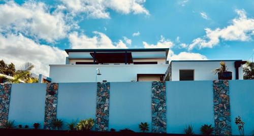 a white house with blue walls and palm trees at Blue Naiade Villa zen and cosy in Étang-Salé
