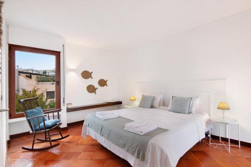 a bedroom with a bed and a chair and a window at Apartamento Balaia Praia in Albufeira