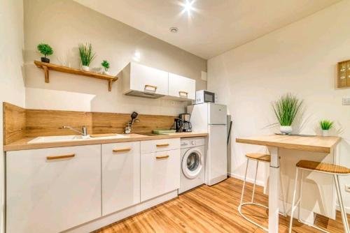 une cuisine avec des armoires blanches, un évier et un lave-vaisselle dans l'établissement Charme en Ville, à Romans-sur-Isère