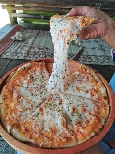 a person taking a slice of cheese pizza at Harry's Ocean House Watukarung Homestay in Kalak