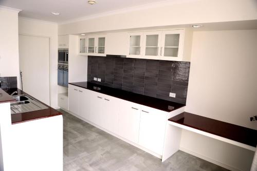 a kitchen with white cabinets and a black tile wall at Salamanca Inn in Hobart
