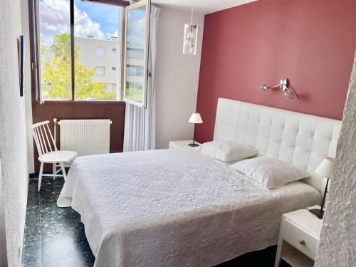 une chambre avec un lit blanc et une fenêtre dans l'établissement LE GRAU DU ROI - SECTEUR RIVES GAUCHE - APPARTEMENT 2 CHAMBRES VUE MER ET PARKING, au Grau-du-Roi