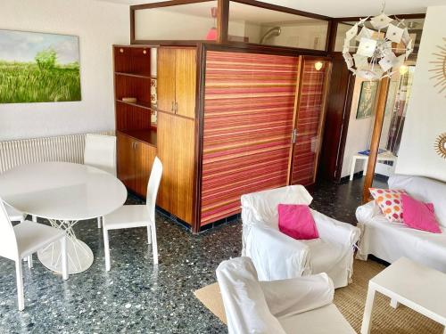 un salon avec une table et des chaises blanches dans l'établissement LE GRAU DU ROI - SECTEUR RIVES GAUCHE - APPARTEMENT 2 CHAMBRES VUE MER ET PARKING, au Grau-du-Roi